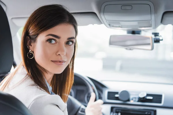 Young Woman Looking Back While Driving Car Blurred Background — Stock Photo, Image