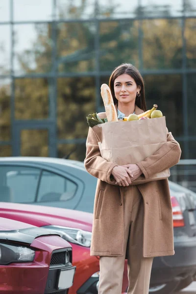 Młoda Kobieta Płaszczu Niosąca Torbę Zakupy Jedzeniem Podczas Spaceru Parkingu — Zdjęcie stockowe