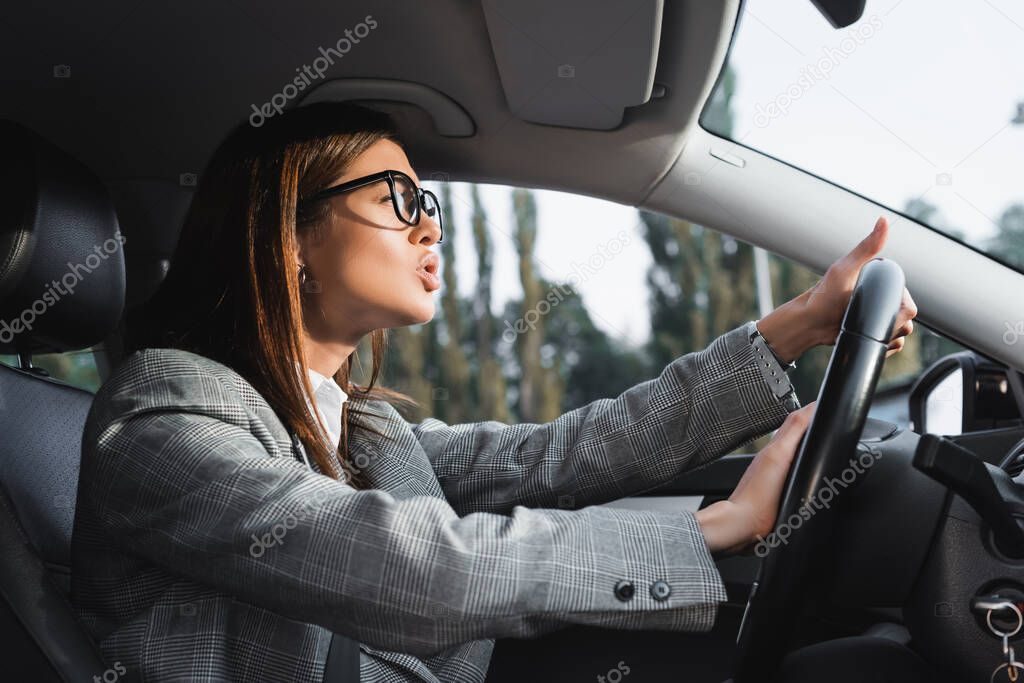 displeased businesswoman looking ahead and beeping while driving car
