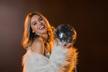 Sahte kürklü mutlu sarışın kadın elinde disko topu tutuyor. 