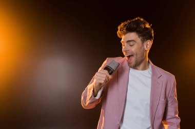 Adam elinde mikrofonla şarkı söylüyor.