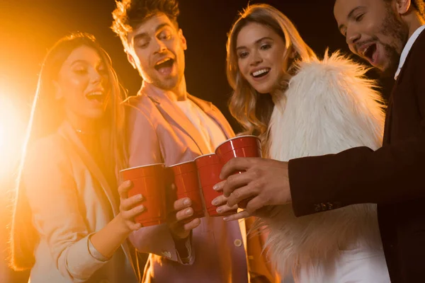 Glückliche Interrassische Freunde Die Plastikbecher Auf Schwarz Anstoßen — Stockfoto