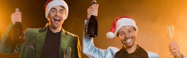 Upphetsad Rasblandad Män Santa Hattar Hålla Flaskor Champagne Och Glasögon — Stockfoto