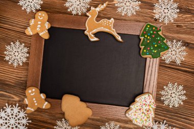 Karatahtadaki kar tanelerinin ve ahşap zemindeki Noel kurabiyelerinin üst görüntüsü