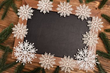 top view of winter snowflakes on chalkboard on wooden background clipart