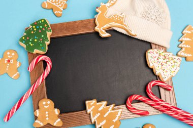 top view of gingerbread cookies and chalkboard on blue background clipart