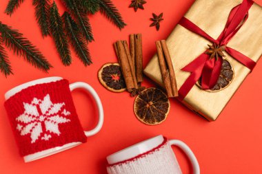 Noel ağacının üst manzarası, kırmızı arka planda baharatlar ve kupalar.