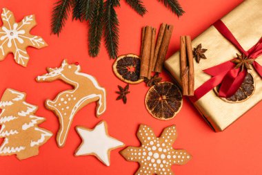 Noel ağacı manzarası, baharatlı hediye ve kırmızı arka planda zencefilli kurabiye.
