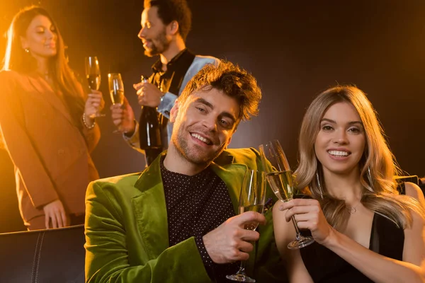 Happy Couple Toasting Glasses Champagne Smiling Multicultural Friends Blurred Black — Stock Photo, Image