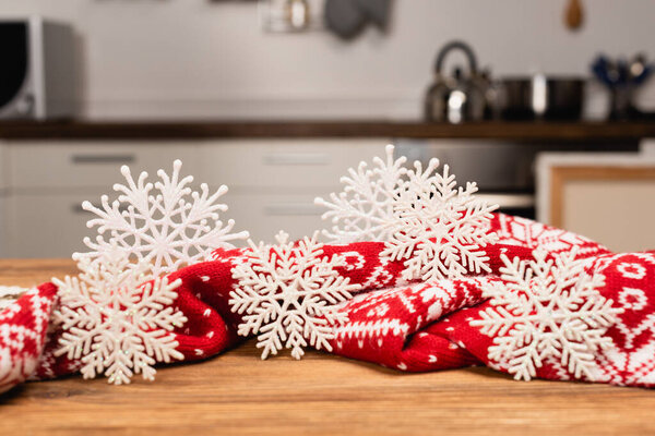 зимние снежинки и вязаный красный шарф на деревянном столе