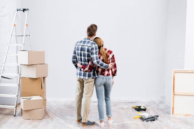 Merdiven, karton kutular ve boya rulolarının yanında sarılan genç çiftin arka plan görüntüsü