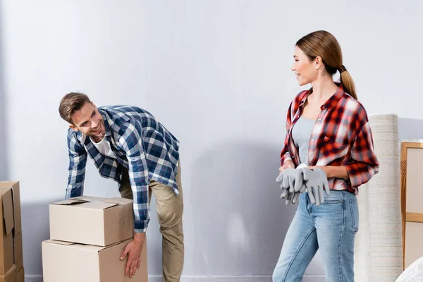 Sonriente Joven Con Guantes Mirando Hombre Sosteniendo Cajas Cartón Casa —  Fotos de Stock