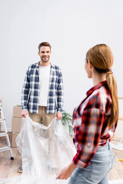 Happy Young Man Looking Blurred Woman While Covering Room Polyethylene — Stock Photo, Image