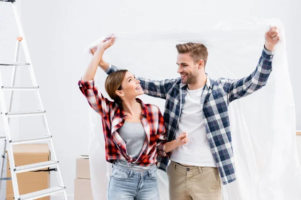 Feliz Pareja Joven Con Cubierta Polietileno Casa — Foto de Stock