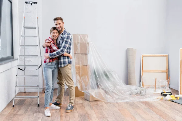 Comprimento Total Feliz Jovem Casal Olhando Para Câmera Enquanto Abraçando — Fotografia de Stock