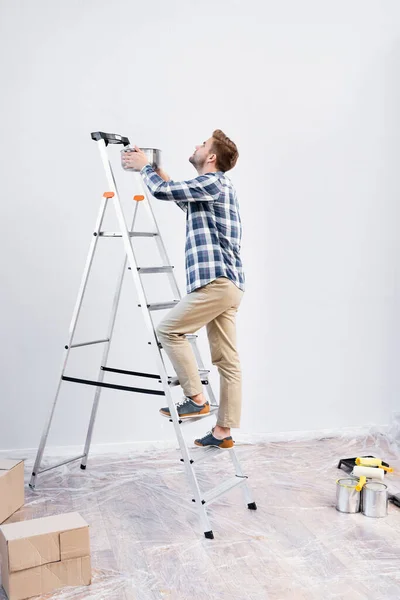 Junge Mann Mit Topf Steht Hause Auf Leiter Unter Undichter — Stockfoto