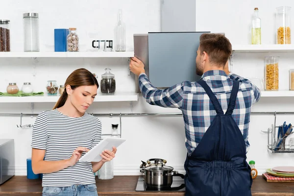 Jovem Mulher Usando Tablet Perto Handyman Reparação Extrator Ventilador Cozinha — Fotografia de Stock