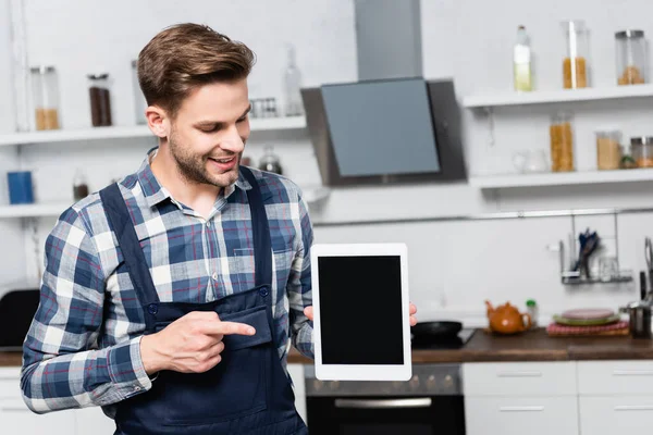 Reparador Feliz Apontando Com Dedo Para Tablet Com Cozinha Embaçada — Fotografia de Stock