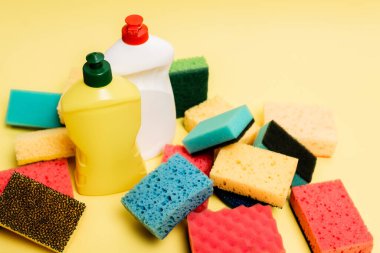 High angle view of dishwashing liquid and sponges on yellow background clipart