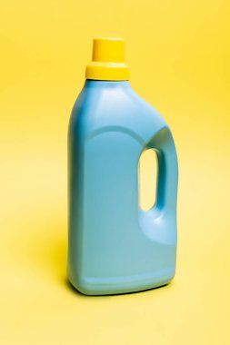 Sarı arka planda mavi bir deterjan şişesi.