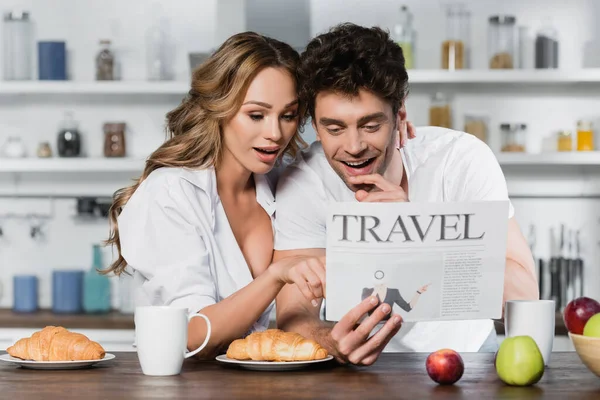 性感女人在微笑的男友身边阅读旅行新闻 并在桌上享用早餐 — 图库照片