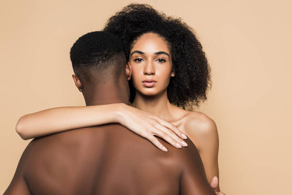 curly african american woman embracing boyfriend isolated on beige