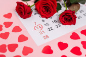 Únorový kalendář se srdcem a růžemi na růžovém pozadí