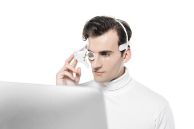 Göz merceğindeki ve kulaklıktaki Cyborg, beyaz önplandaki bulanık bilgisayara bakıyor.