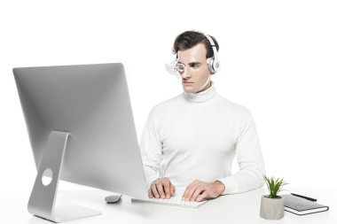 Göz merceğindeki ve kulaklıktaki Cyborg bitkinin yanındaki bilgisayarı kullanıyor ve beyaz defter üzerinde izole edilmiş.