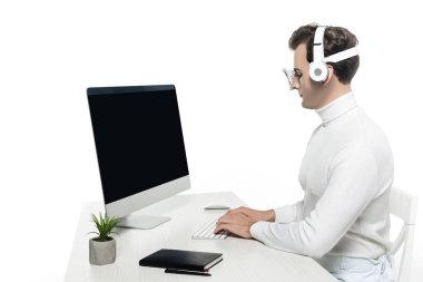 Kulaklıklarda bilgisayar kullanan Cyborg bitkinin yanında boş ekran ve beyaz masada izole edilmiş defter kullanıyor.