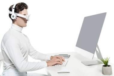 Kulaklıklarda ve dijital göz merceğinde Cyborg, bilgisayarla defter yakınındaki boş ekranı kullanıyor ve ön plandaki bulanık bitkiyi beyaza bağlıyor.