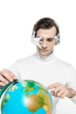Göz mercekli ve kulaklıklı Cyborg adam beyaz önplanda bulanık ön planda dünyayı işaret ediyor.