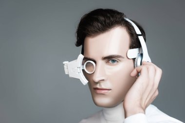 Dijital gözlüklü Cyborg adam gri renkte izole edilmiş kulaklıkları ayarlıyor.