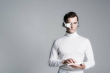 Kulaklıklı ve gözlüklü Cyborg adam gri üzerinde izole edilmiş bilgisayar klavyesi kullanıyor.