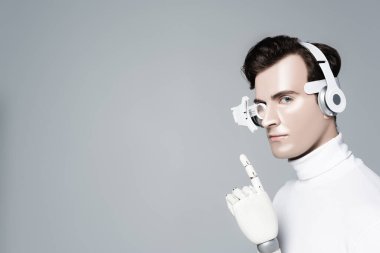 Kulaklıklı, yapay elli Cyborg adam gri üzerine parmak işareti yapıyor.