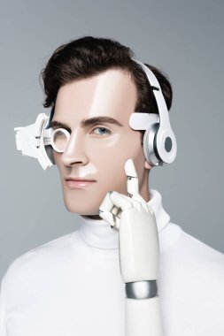 Kulaklıklı bir Cyborg. Yapay elli. Gri renkli kameraya bakıyor.