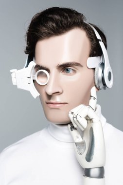 Dijital göz merceği, kulaklık ve yapay el takmış Cyborg adam griye bakıyor.