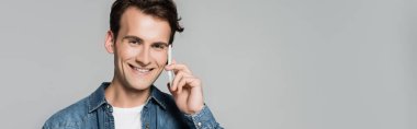 Akıllı telefondan konuşan gülümseyen adam, gri pankartta izole edilmiş.