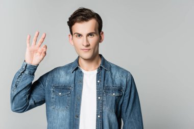 Kot ceketli esmer adam gri üzerine izole edilmiş bir jest gösteriyor.