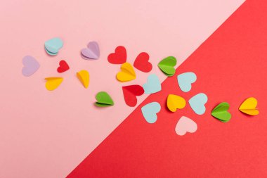 Kırmızı ve pembe arkaplanda renkli kağıt kalplerin üst görünümü