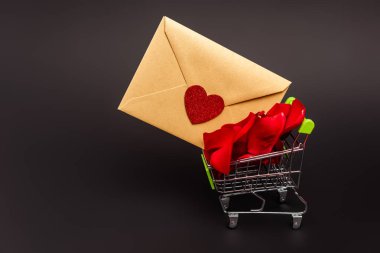 Üzerinde gül yaprakları ve siyah bir zarf olan alışveriş arabası.