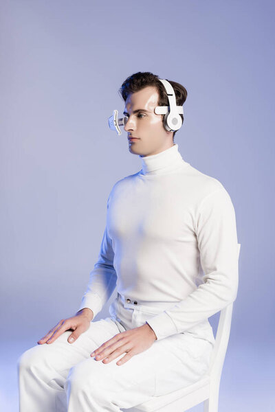 Cyborg in headphones and digital lens sitting on chair isolated on blue