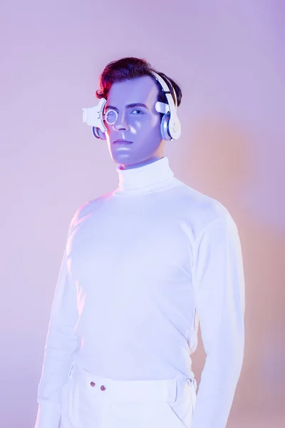Cyborg Białych Ubraniach Słuchawkach Patrząc Aparat Fotograficzny Fioletowym Tle — Zdjęcie stockowe