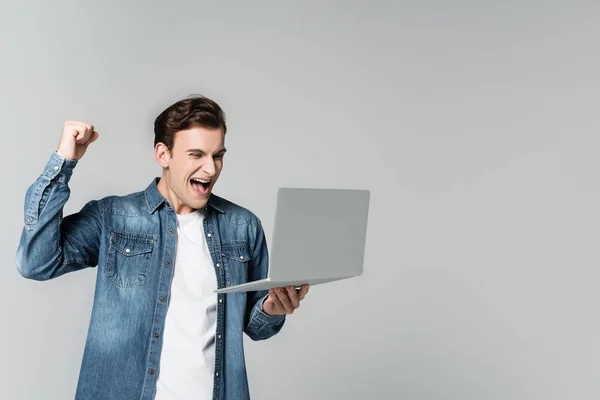 Веселий Чоловік Показує Жест Тримаючи Ноутбук Ізольований Сірому — стокове фото