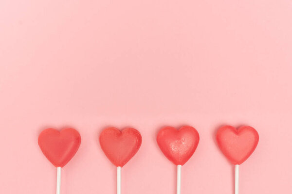 top view of heart shaped lollipops on pink background