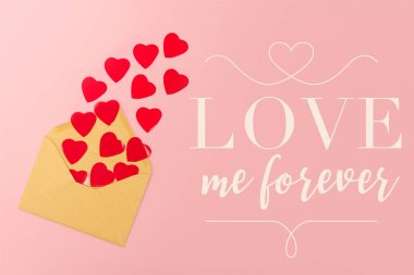 top view of red paper hearts and envelope near love me forever lettering on pink background clipart