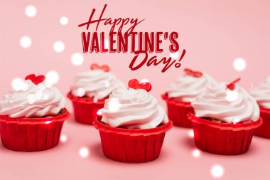 tasty cupcakes with red hearts near happy valentines day lettering on pink background clipart