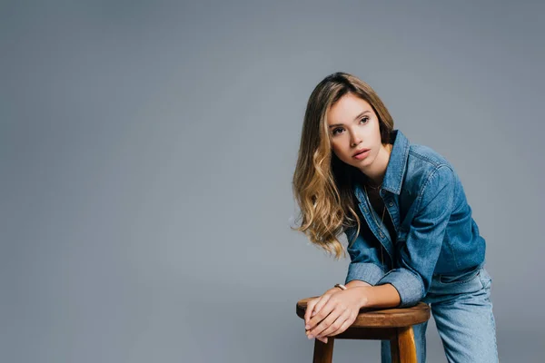 Jovem Mulher Camisa Jeans Olhando Embora Enquanto Inclina Cadeira Alta — Fotografia de Stock