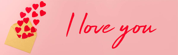 Top view of red paper hearts and envelope near i love you lettering on pink background, banner