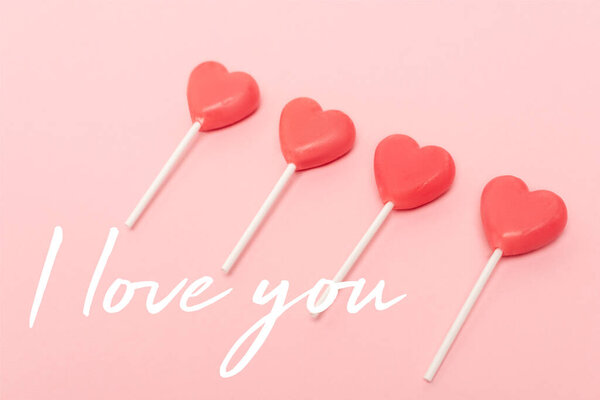 Леденцы в форме сердца рядом Я люблю тебя буквы на розовом фоне